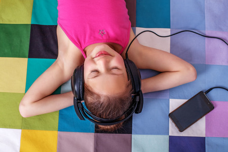 Little girl lying and listening to music. The concept of childhood and music.の写真素材