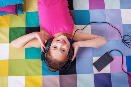 Happy Child lying and listening to music. The concept of childhood and music.の写真素材