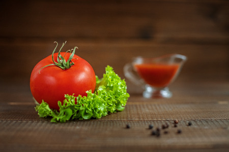Sauce, lettuce and tomatoes on a wooden background. The concept of healthy eating and vegetarianism.の写真素材