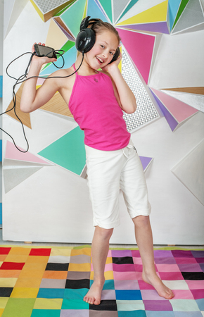 Child girl listens to music and dances. The concept of music and childhood.の写真素材