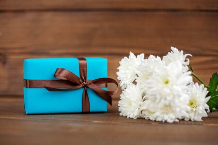Wooden background with a gift and flowers for congratulations. The concept of Mother's Day, birthday, March 8.の写真素材
