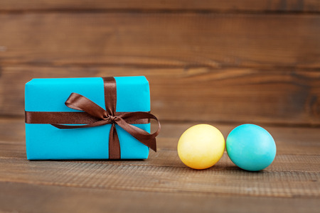 Light blue and yellow Easter eggs and the box on a wooden background. Place for inscription. Concept Happy Easter.の写真素材
