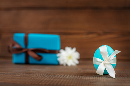 Light blue egg and a gift on a wooden background. Place for inscription. Concept Happy Easter.の写真素材