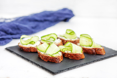 Sandwiches with cheese feta and cucumber on shale board. The concept of food and vegetarianism.の写真素材