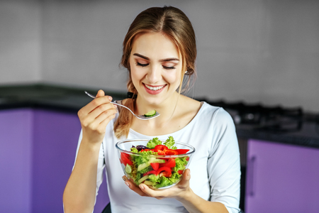 A young girl eats a delicious vegetable salad. The concept is heの写真素材