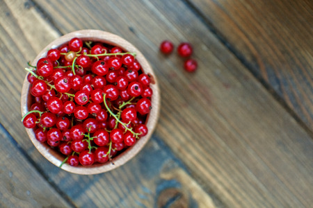 Red currant in the bowl. Wooden background. The concept is healthy food, vitamins, diet and vegetarianism.の写真素材