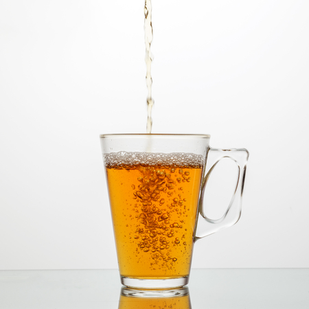 Pour tasty tea into a glass cup. The concept of dishes and drinks.の写真素材