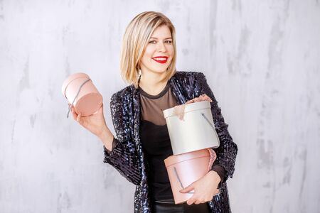 A successful blonde woman keeps gift boxes. Concept surprise, holiday, Valentine's Day, March 8,...