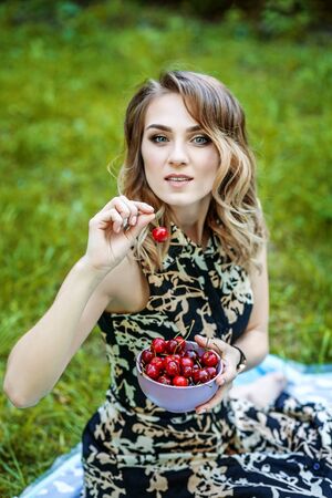 Happy girl holds a bowl of cherries. Hot summer. The concept is healthy food and lifestyle.の写真素材