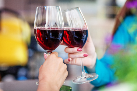 Glasses of red wine in their hands. Toast. The concept of party and celebration.の写真素材