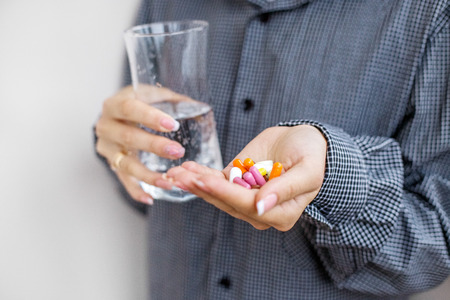 Pills and vitamins and a glass of water in your hands.Concept illness, colds, cure, fall and winter.の写真素材