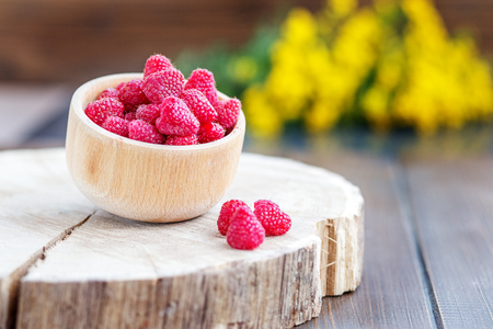 Fresh juicy raspberries in a wooden bowl. The concept is healthy food, diet, vegetarianism, vitamins.の写真素材