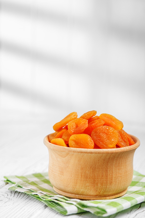 A useful dried apricot in a wooden bowl. The concept is healthy food, vegetarianism, diet, vitamins.の写真素材