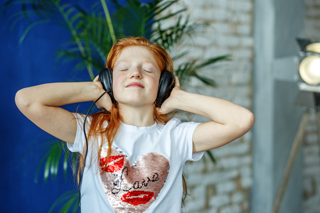 An emotional child listens to songs in the headphones and dances. The concept is childhood, lifestyle, music, singing, listening, hobbies.の写真素材