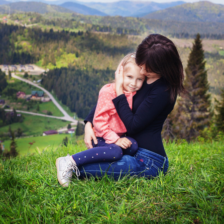 Mom hugs a little daughter at the top of the mountain. Square. The concept of family, yoga, travel.の写真素材