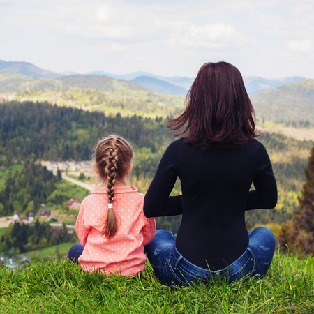 Mom and little daughter are meditating on the top of the mountain. Square. The concept of family, yoga, travel.の写真素材