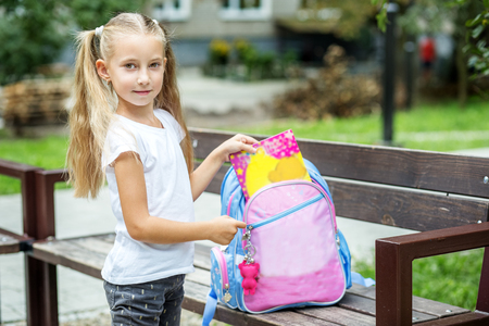A little girl is laying books in her school backpack. The concept of school, study, education, friendship, childhood.の写真素材