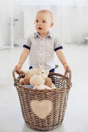 A small child holds a basket with toys. The concept of childhood