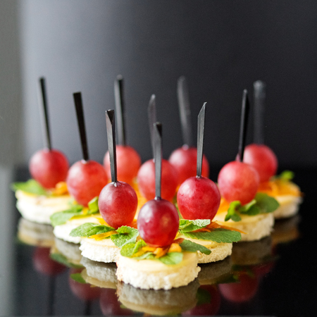 A lot of canapes with toast bread, cheese and grapes. Copy space. Concept for food, snacks, menu, restaurant, catering.の写真素材