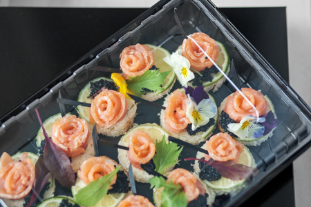 Delicious appetizer with fish and edible flowers in lunch box. Concept for food, restaurant, menu, catering.の写真素材