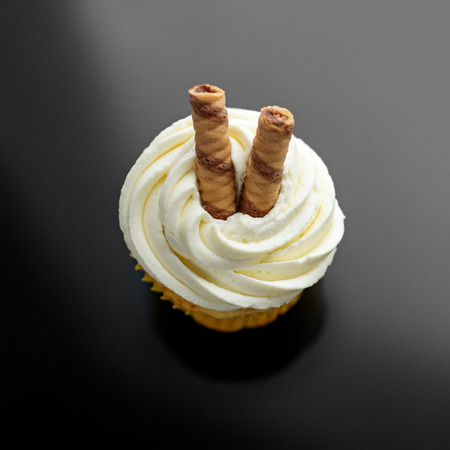 Sweet yummy cupcake with cream and wafer rolls. View from above. The concept of food, desserts, holiday.の写真素材