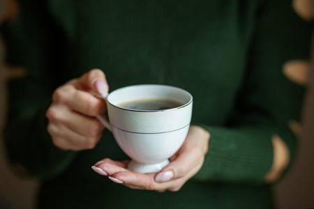 A cup of hot coffee in the hands. Concept drinks, lifestyle, work, backgroundの写真素材