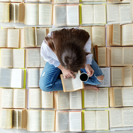 A young student reads a book and drinks coffee. Top view. Concept for World Book Day, lifestyle, study, educationの写真素材
