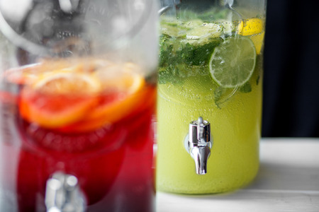 Refreshing lemonade with lime, mint, orange and pomegranate in glass jars with faucet. Concept of drinks, summer, bar, rest, healthy foodの写真素材
