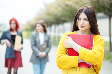 A beautiful woman is standing with a folder. Education concept, exams, friendship and group of peopleの写真素材