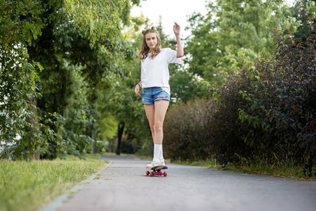 A young girl is riding a skate board in the park. The concept of lifestyle, leisure, hobby.の写真素材