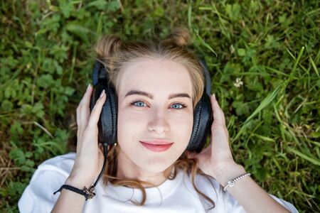 A young woman is listening to an audiobook with headphones. Concept of lifestyle, music and leisure.