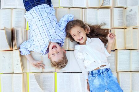 Children lie on a lot of books. The kids are laughing. Top view. The concept is back to school, education, reading, friendship and family.の写真素材