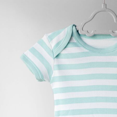 Striped clean clothes for a newborn on a hanger. Place for text. The concept of clothes, motherhood, fashion and newborn.の写真素材