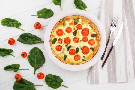 Quiche pie with spinach, cherry and mozzarella. Cutlery on a napkin. The concept of delicious food, recipes, bakery.の写真素材