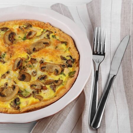 Quiche pie with chicken and mushrooms. Cutlery on a napkin. Square. Close-up. The concept of food, breakfast, restaurant.の写真素材