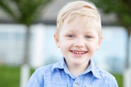 The blue-eyed child is smiling. The little boy is blond. The concept of childhood, back to school,...