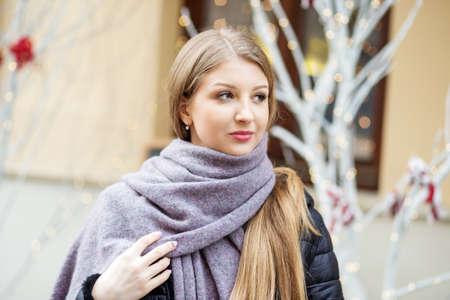 Portrait of a girl in a hat and whitescarf, a walk through the Christmas city, a smile on her face,...