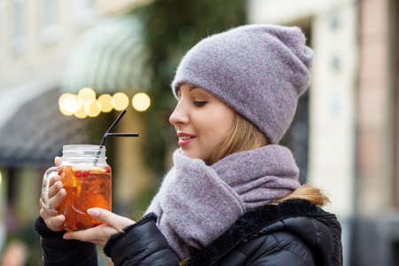 Happy young girl with a fluttering scarf walks through the Christmas streets of the city. Grace and...