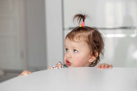 A little girl in the kitchen stares away from the camera.の写真素材