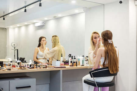Makeup Brush. Apply makeup to face. Cozy beauty salon. Skin care. Small business. Two women....