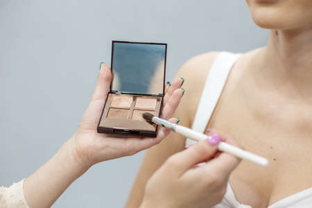 Makeup artist blonde prepares cosmetics for make-up. Pale brown eyeshadow palette.の写真素材