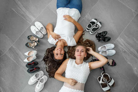 Two women are lying on the floor. Lots of womens shoes. Top view.の写真素材