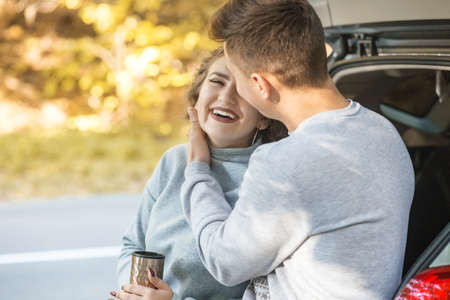 A loving couple walks in the autumn forest. Hot tea in a thermo mug. Happy laugh.の写真素材