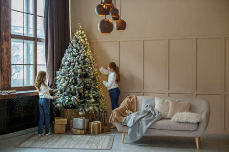 Cozy home. Modern interior in beige tones. Happy sisters. Preparing for Christmas.の写真素材