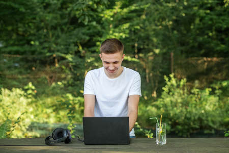 Young guy smiles happily while making video call using laptop.