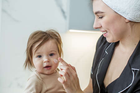 Young mother with baby in towels after shower in bathroom. Concept of hygiene and cleanliness, hygiene procedures with child.の写真素材