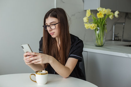Smiling woman reads phone message. Brunette happy girl is typing text message. Bouquet of yellow...