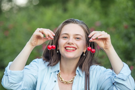 Image of young girl with cherry on background of nature. summer season. lifestyle concept.