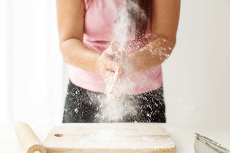 Making dough by hand in a bakery or at home. Flour cloud in the waterfall. Women's hands. cutting...