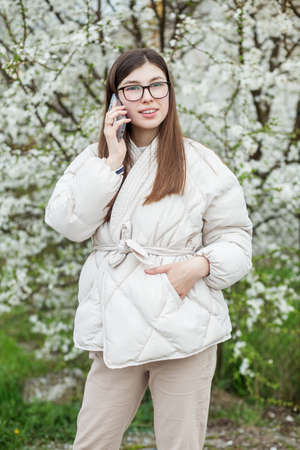 Portrait of girl in eyeglasses near flowering tree. Long healthy hair.の写真素材